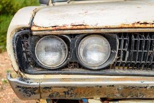 An old car with rust deposits on the chrome bumper.