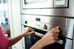 A women adjusts the temperature on an oven