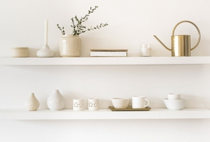 floating shelves with simple ceramic items and brass watering can