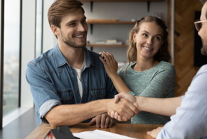 smiling couple shaking hands with a landlord