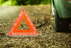 An emergency triangle next to a car tire.