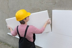 Worker installing foam board onto a cement wall