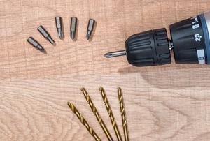 Drill bits and a drill on a wooden surface.