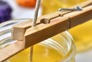 clothespin holding a wick in cooling wax in a jar