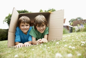 A couple of boys playing in a large cardboard box.