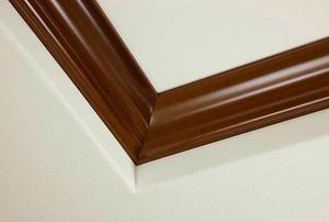 A corner of ceiling with brown crown molding.