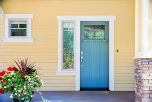 front porch with flowers in a pot and blue door
