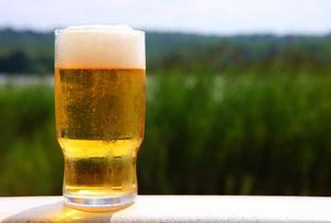 Foamy beer sitting on a white rail.