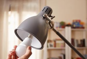 A light bulb being inserted into a lamp.
