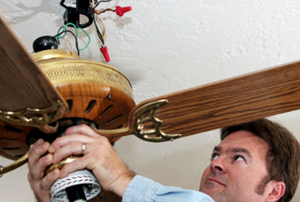 man working on a ceiling fan fixture
