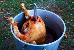 A turkey deep frying in a backyard.