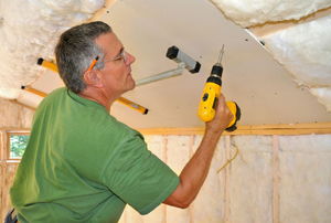 man drilling a hole into the ceiling