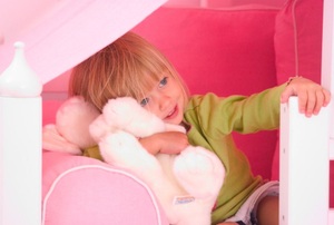 A little girl in a pink bed.