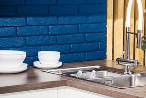 kitchen sink, coffee cups, and blue painted brick backsplash