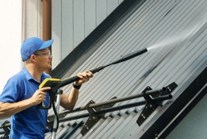 A man washes a metal roof.