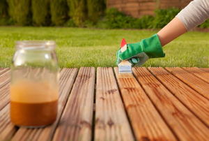 A man stains a wood deck.