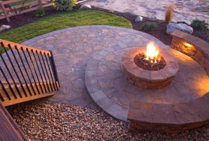 Circular fire pit at dusk on a flagstone patio.