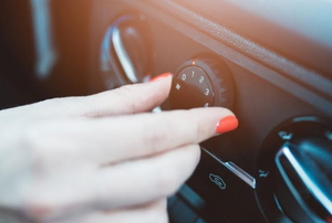 A female hand adjusting the vent on a car dashboard.