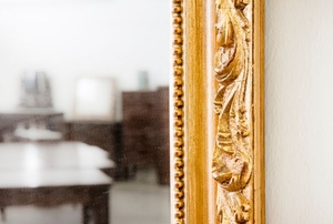 A wall mirror with a gold painted frame.