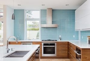 Large kitchen with white upper cabinets, wood lower cabinets and teal blue tile backsplash