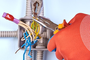 gloved hands with pliers splicing wires