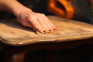 a hand sanding a wooden table