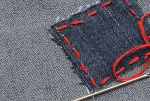 red thread holding a blue patch on denim fabric