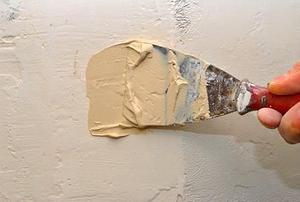 Close-up of someone applying mud to drywall.