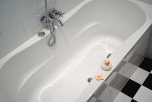 An empty bathtub with a waiting rubber ducky.
