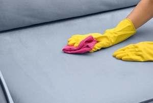 A women cleans a stain on a couch.