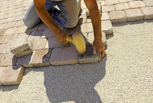 person installing tan brick pavers
