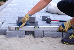person with level installing paver walkway stones