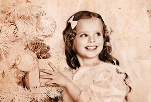 A retro looking photo of a girl next to Christmas tree.