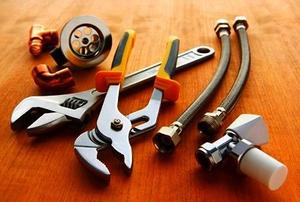 Plumbing tools and materials on wooden floor.