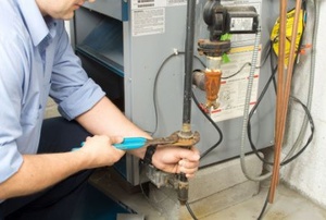 man repairing furnace with pliers