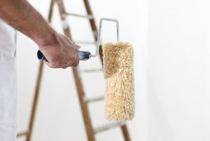 A clean paint roller with a ladder in the background. 