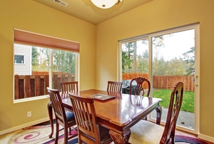 A dining room with a sliding glass door leading out to a backyard patio.