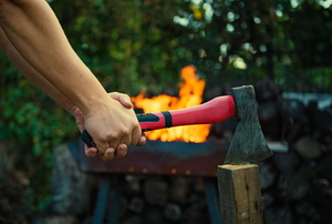 A hand axe (camping axe) is held in front of a fire.