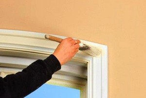 A painter working on trim in a doorway.