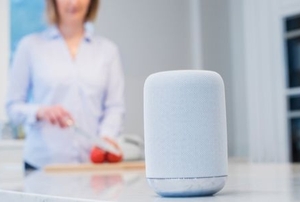 a woman cuts fruit in a kitchen with a smart home hub