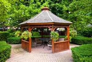 A pergola in landscaped garden with an interlocking paver patio.