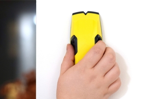 hand using stud finder on wall