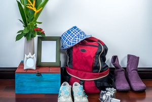 A grouping of random household items including a backpack, shoes, and a vase with fake flowers.