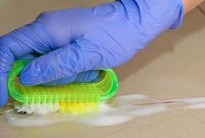 Gloved hand scrubbing grout