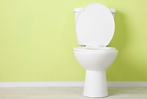 A toilet on a lime green wall.