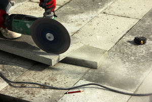Concrete saw cutting through a paver slab