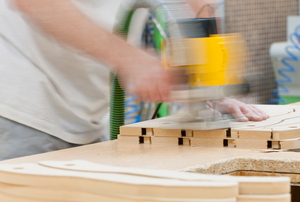 A woodworker using a router on medium density fiberboard.