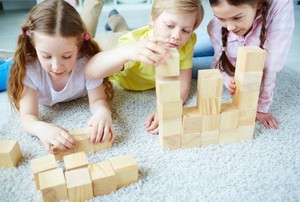 three children playing with wooden blocks