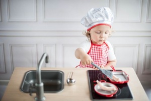 A toddler pretending to cook in his play kitchen.