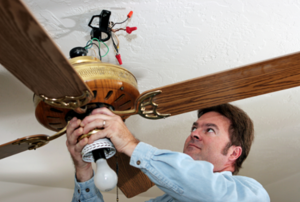 man working on a ceiling fan fixture